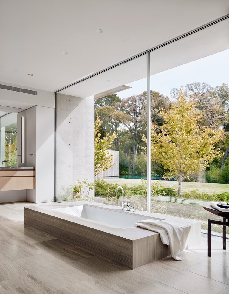 The bathroom features a built in tub placed next to a glass wall to enjoy the views