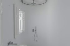 08 The bathroom is pure white, with a small shower space and a wall-mounted sink, the original shutters preserved