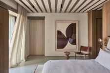 08 The master bedroom shows off wooden panels, a comfy bed, sconces and a statement artwork