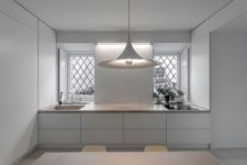 10 The kitchen is pure white, with sleekcabinets, a stone countertop, a cool pendant lamp