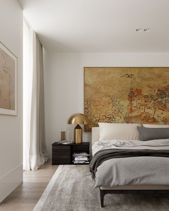 a chic and stylish bedroom with a statement artwork and bold brass lamps that add chic and a cool look to the space