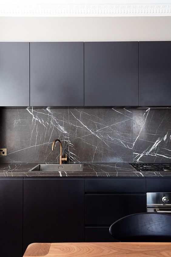 a minimalist midnight blue kitchen with a black marble backsplash and countertop that give it an ultimate luxe look and feel