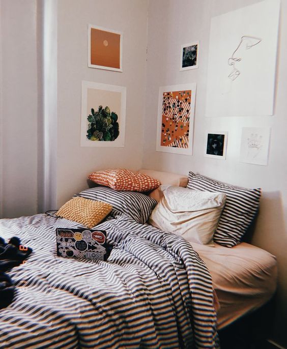 A pretty and bright gallery wall that hangs over the bed instead of a headboard and continues to the next wall