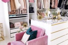 14 a small glam closet with lots of holders with hangers, shelves and drawers, a large dresser and a pink chair