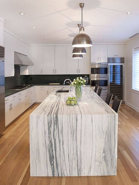 a monochromatic kitchen with a gorgeous kitchen island that features a white marble countertop and makes a statement