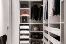 16 a small minimalist closet with holders for hangers, lots of drawers, open shelves and a single black chair