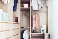 20 a small stylish closet done in light stained wood, with holders for clothes hangers, some open shelves, built-in drawers and a black chair