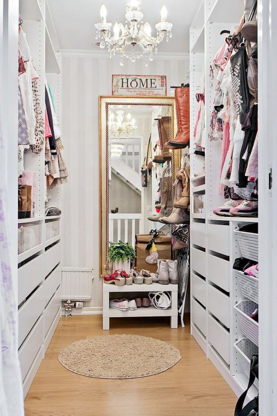 a small vintage-inspired sweet closet with a large mirror, a crystal chandelier, open shelves and holders plus drawers