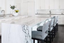 21 an elegant white kitchen with a chic kitchen island with a white marble waterfall countertop that brings luxe here
