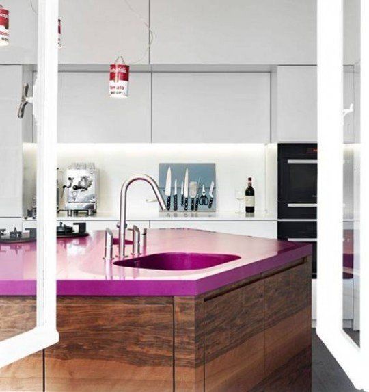 a sleek minimalist white kitchen and a dark stained kitchen island with a fuchsia countertop that makes a bold statement here