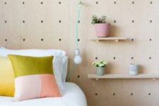 26 a pegboard wall with various shelves, potted blooms and greenery and even a bulb attached for more functionality