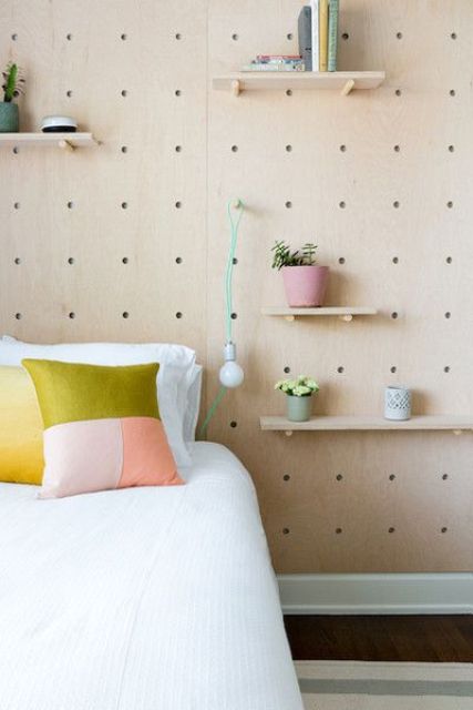 a pegboard wall with various shelves, potted blooms and greenery and even a bulb attached for more functionality