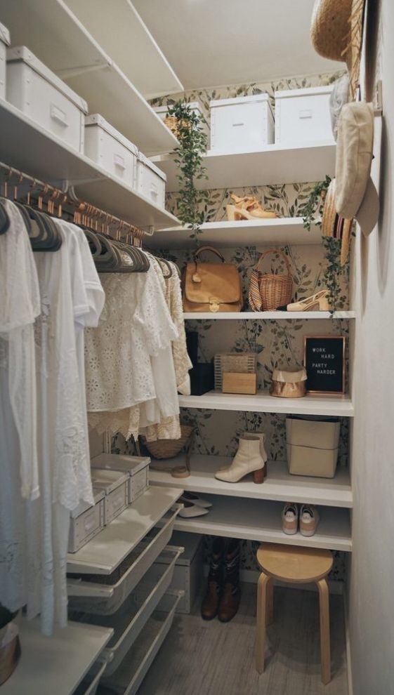 a tiny girlish closet with botanical wallpaper, a faux cascading plant, open shelves, some cubbies, holders for hangers and a wooden stool