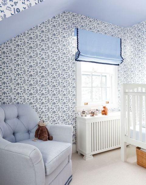 a blue cottage nursery with wallpaper walls, blue textiles and upholstery plus white furniture