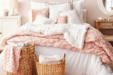 a blush bedroom with a bed with pink and white bedding, mismatching nightstands, baskets and an open shelf