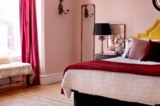 a bold whimsical bedroom with pink walls, fuchsia curtains, statement pillows, a black bed and lamps