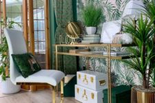 a bright and glam tropical home office with an accent wall, green and white boxes, a gold glass desk, brass planters and a glam chair