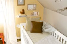 a bright attic nursery with a yellow accent wall, cozy textiles and a rug plus a small gallery wall and branches for a natural touch