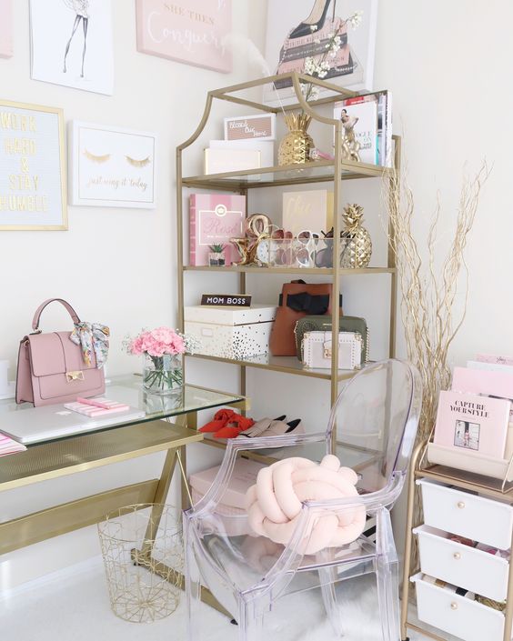 a chic home office with pink books and accessories, with a pink knot pillow and bag and touches of gold