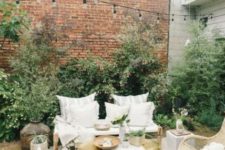 a chic small patio with a rug, some pillows, potted greenery, baskets and wooden and wicker furniture
