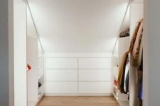 a cool modern attic ceiling closet with open shelves with built-in lights and a built-in dresser is a very practical solution