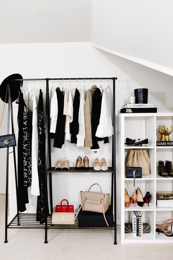 a cool modern makeshift closet with a black clothes rack, a white storage unit and lots of cool clothes and shoes on display