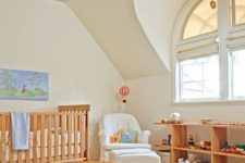 a cozy and simple attic nursery with a blue ceiling, wooden furniture, toys and a vintage chandelier