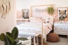 a creative boho bedroom with color block pink walls, a jute rug, a crochet ottoman, greenery and macrame hangings