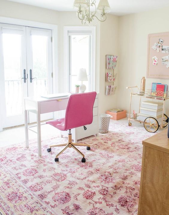 a cute eclectic home office with a hot pink chair, floral printed pink rug and some more accessories that add a girlish feel