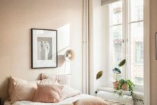 a delicate blush bedroom with a bed and neutral and blush bedding, an artwork and potted greenery is lovely