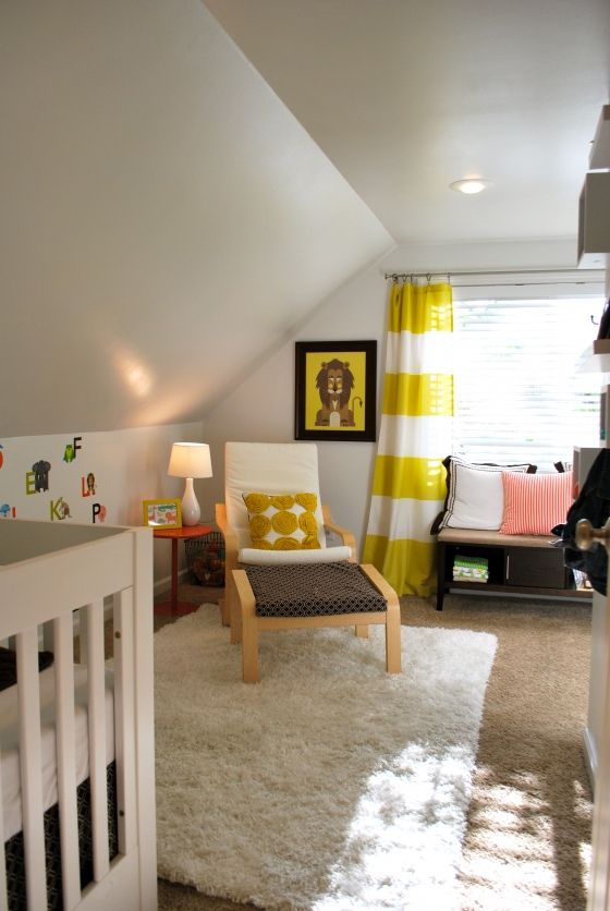 a gender neutral attic nursery with an IKEA chair, crib, bright yellow and black touches and bright pillows