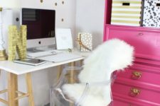 a glam home office with a hot pink storage unit and a pink and gold glitter garland plus an acrylic chair