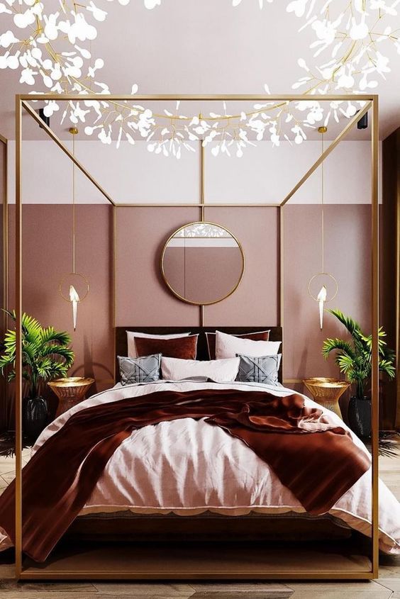 a gorgeous glam bedroom with pink color block walls, a brass bed, a cool chandelier, greeneyr in pots and parrot pendant lamps