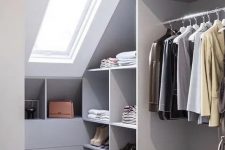 a grey attic closet with open storage compartments, drawers and railings plus a skylight for more natural light
