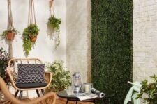 a lovely patio with wicker chairs, a coffee table, a greenery wall and some potted greenery is very welcoming