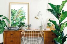 a mid-century modern home office in neutrals, with a vintage wooden desj, potted plants and a tropical artwork