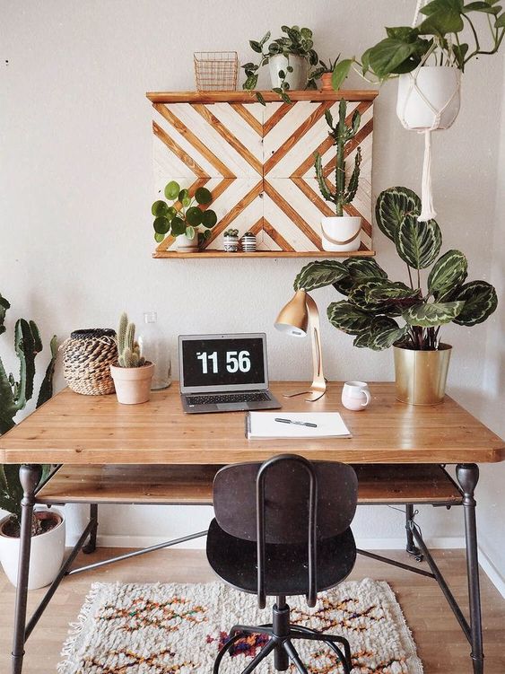 a mid-century modern tropical home office with a wooden desk and a vintage metal chair, potted plants and cacti plus a chevron artwork
