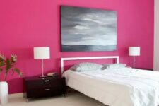 a minimalist bedroom with a hot pink accent wall, a simple bed and nightstands, a table lamp and a moody artwork