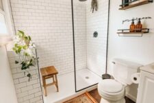 a modern farmhouse bathroom with white subway tiles, a wooden floor, white furniture, potted greenery and a boho rug