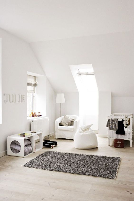 a modern neutral nursery with two windows, white furniture, a rug and lots of storage units for a littel kid