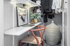 a narrow closet done with open shelves, railings, a shelf that is a desk, a chair, a basket with a lid and some lights