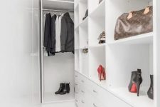 a narrow white walk-in closet with railing, open storage compartments, drawers and some clothes and shoes