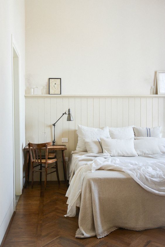 a neutral bedroom with neutral beadboard, a wooden desk and chair, some vintage touches here and there