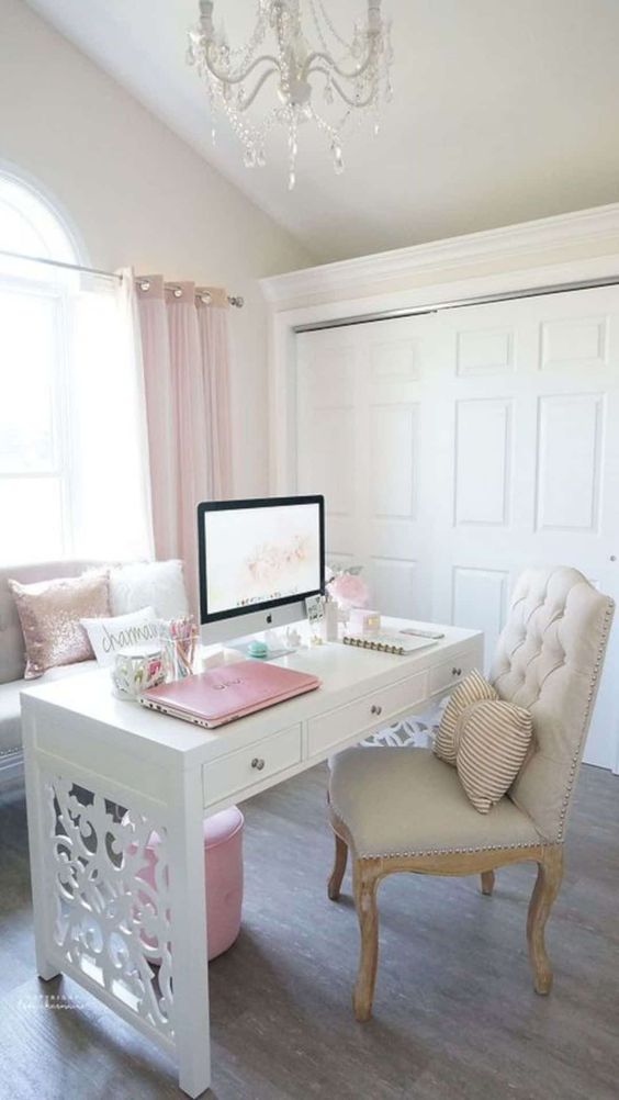 A neutral vintage inspired home office with pink curtains, pillows, an ottoman and even a laptop for a cute look