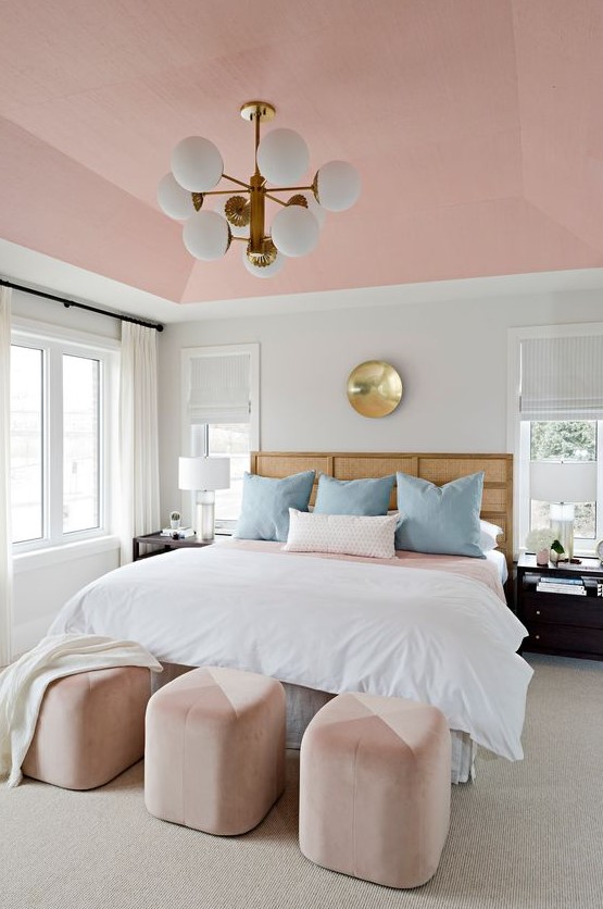 A refined mid century modern bedroom with a pink ceiling, pink and blush ottomans for softening the color scheme
