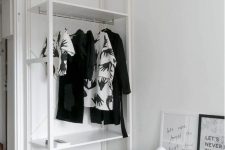a small Scandinavian makeshift closet with shelves and a rack with clothes hangers plus a basket are great for those with a minimal wardrobe