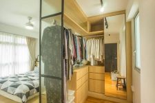 a small and cool closet with a glass wall, rails with hangers, some drawers and a mirror cabinet is a very edgy idea for a bedroom