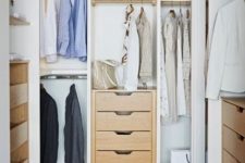 a small and cute closet with built-in shelves, drawers, built-in lights and a woven pouf plus racks for clothes