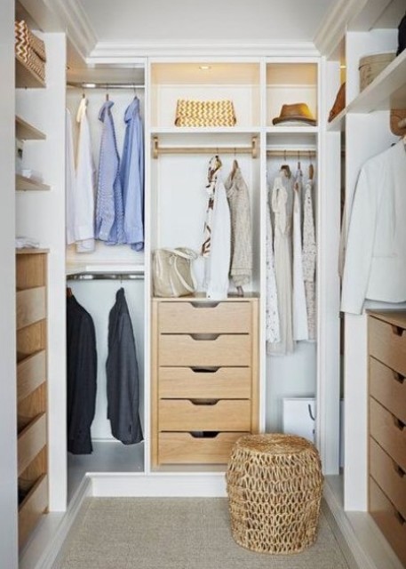 A small and cute closet with built in shelves, drawers, built in lights and a woven pouf plus racks for clothes