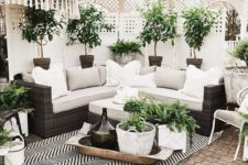 a small and elegant patio in a monochromatic color scheme, with a printed rug, a wicker sofa, potted greenery and some baskets